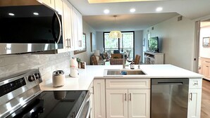 A modern kitchen with stainless steel appliances, white cabinetry, and a central island. - New! Just renovated coastal condo, Gated community, 10 min to beach by shuttle!  (Bonita Springs)