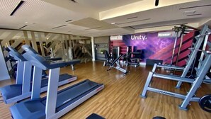 Un gimnasio con cintas de correr, máquinas de pesas y una pared con temática de Unity.