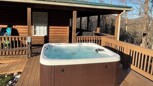 Une cabane en bois avec un jacuzzi sur une terrasse.