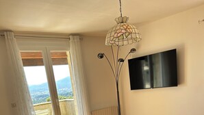 Ein modernes Schlafzimmer mit Bett, einer Couch, einer Stehlampe und einem Fernseher.