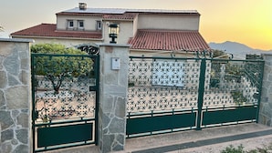 Ein Haus mit einer Steinmauer, einem Metallgitter und einem Ziegeldach.