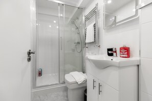 A modern bathroom with a glass-enclosed shower, a white toilet, and a sink with a mirror above it. - Wonderful 2 Bed Apartment near Portobello Road (London)
