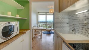 Une cuisine équipée d’un lave-linge intégré, un coin repas avec vue et une grande fenêtre.