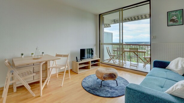 Un salon moderne avec une table à manger en bois, des chaises, un téléviseur et un canapé.