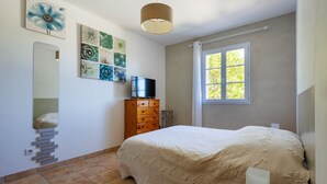 A bedroom with a bed, a dresser, a TV, and artwork on the wall. - La Maison de Mathis - Maison avec piscine privée (Valréas)