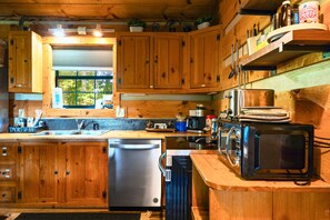 A wooden cabin kitchen with a built-in dishwasher, a coffee maker, and a microwave. - Point of View Cabin · Private Hot Tub, Fire Pit & Mountain Views · Dog-Friendly (Sevierville)