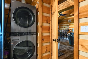 A laundry room with two front-loading washing machines, a wooden interior, and a ceiling fan. - Point of View Cabin · Private Hot Tub, Fire Pit & Mountain Views · Dog-Friendly (Sevierville)