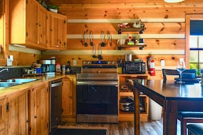 A wooden cabin-style kitchen with a built-in oven, microwave, and coffee maker. - Point of View Cabin · Private Hot Tub, Fire Pit & Mountain Views · Dog-Friendly (Sevierville)