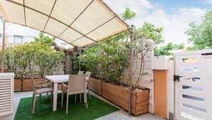 Un patio con una mesa y sillas, rodeado de macetas y una valla de madera.