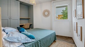Un dormitorio con cama, escritorio y ventana.