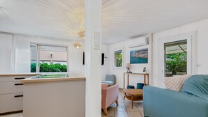 Un espacio habitable compacto con kitchenette, comedor y sala de estar con sofá y sillas.