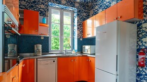 A kitchen with orange cabinets, a white dishwasher, and a white refrigerator.