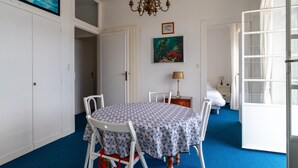 A dining area with a round table, white chairs, a chandelier, and a blue carpet.