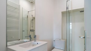 Ein modernes Badezimmer mit Duschkabine aus Glas, Waschbecken in Weiß und Toilette.
