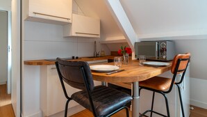 A modern kitchen with a wooden table, two chairs, a microwave, and a radio. - La Timonerie - Studio climatisé à Bénodet (Benodet)