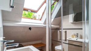 A modern bathroom with a skylight, a bathtub, a shower, and a toilet. - La Timonerie - Studio climatisé à Bénodet (Benodet)
