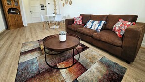 Un salón con un sofá marrón, dos cojines decorativos estampados, una mesita de centro redonda con una suculenta y una alfombra colorida.