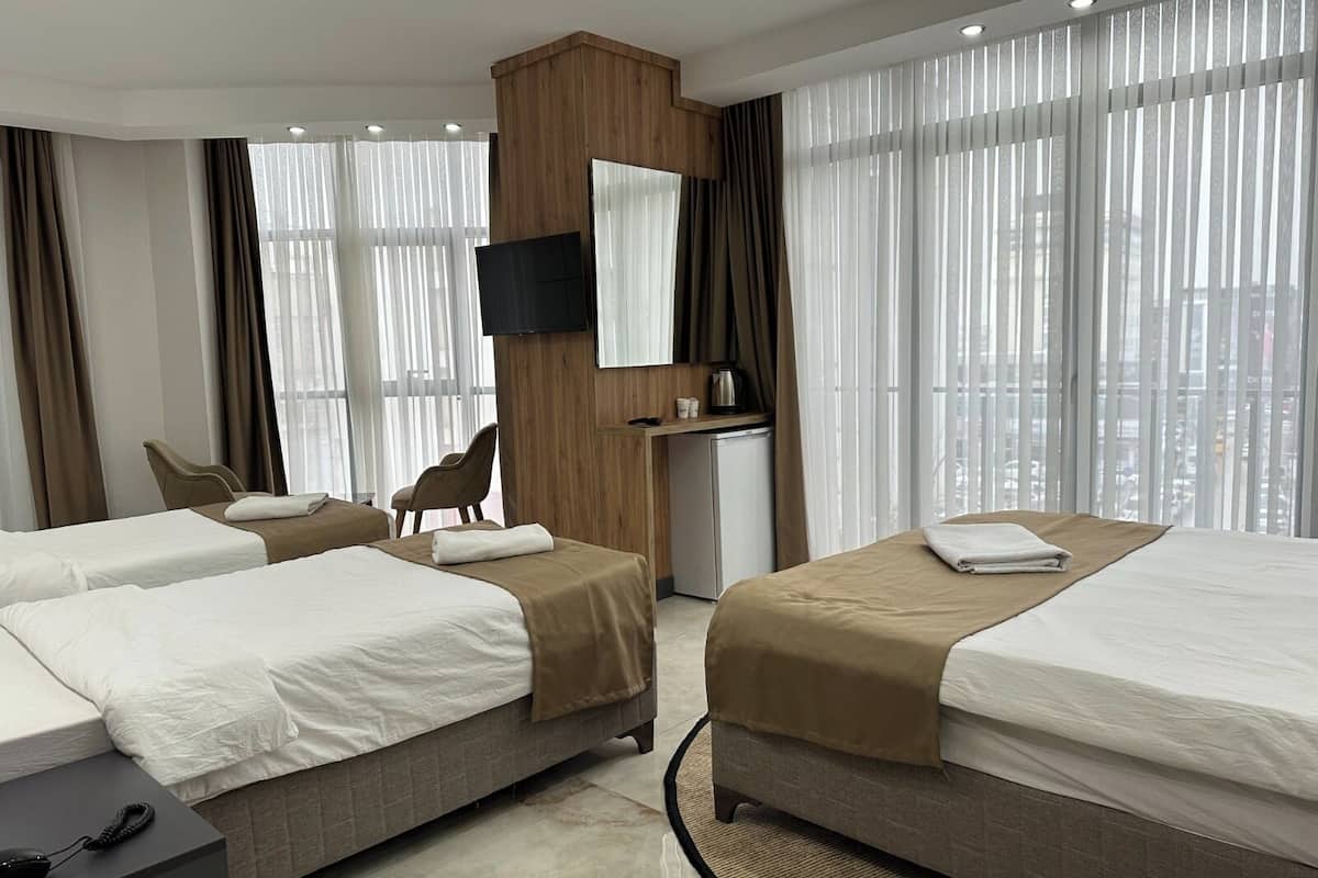 Une chambre d’hôtel avec deux lits, un bureau avec un téléphone, une télévision et une kitchenette.