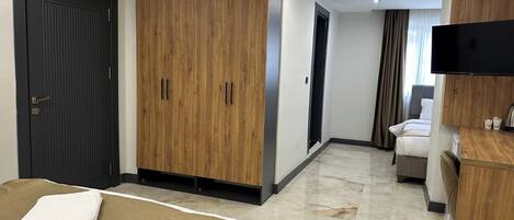 A hotel room with a bed, a wooden wardrobe, a television, and a desk.
