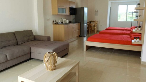 Un soggiorno moderno con un divano, un tavolino in legno e un letto con biancheria rossa.