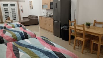 Un espacio habitable compacto con kitchenette, comedor y sofá.