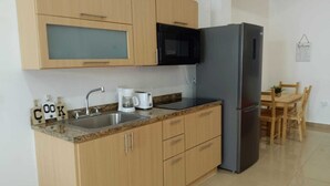 Una cucina compatta con mobili in legno, un lavandino in acciaio inossidabile, un forno a microonde e un frigorifero.