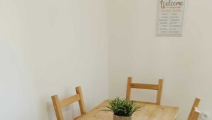 Un tavolo da pranzo in legno con quattro sedie, una piccola pianta in vaso e un cartello di benvenuto appeso al muro.