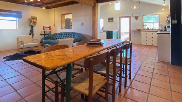Ein rustikales Interieur mit einem Holzesstisch, Stühlen, einem blauen Sofa und einer Küche im Hintergrund.