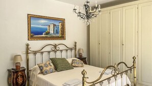 Ein Schlafzimmer mit einem Bett, einer Kandelaber, einem Gemälde und einem Kleiderschrank.