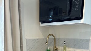 A compact kitchen with a built-in microwave, a sink with a gold faucet, and a small countertop. - LUX 5 - Cozy 1-bed 1bath w/ WiFi, AC in a beautiful neighborhood in Nassau city (Nassau)
