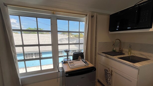 A compact kitchen with a window, a sink, and a built-in microwave. - LUX 5 - Cozy 1-bed 1bath w/ WiFi, AC in a beautiful neighborhood in Nassau city (Nassau)