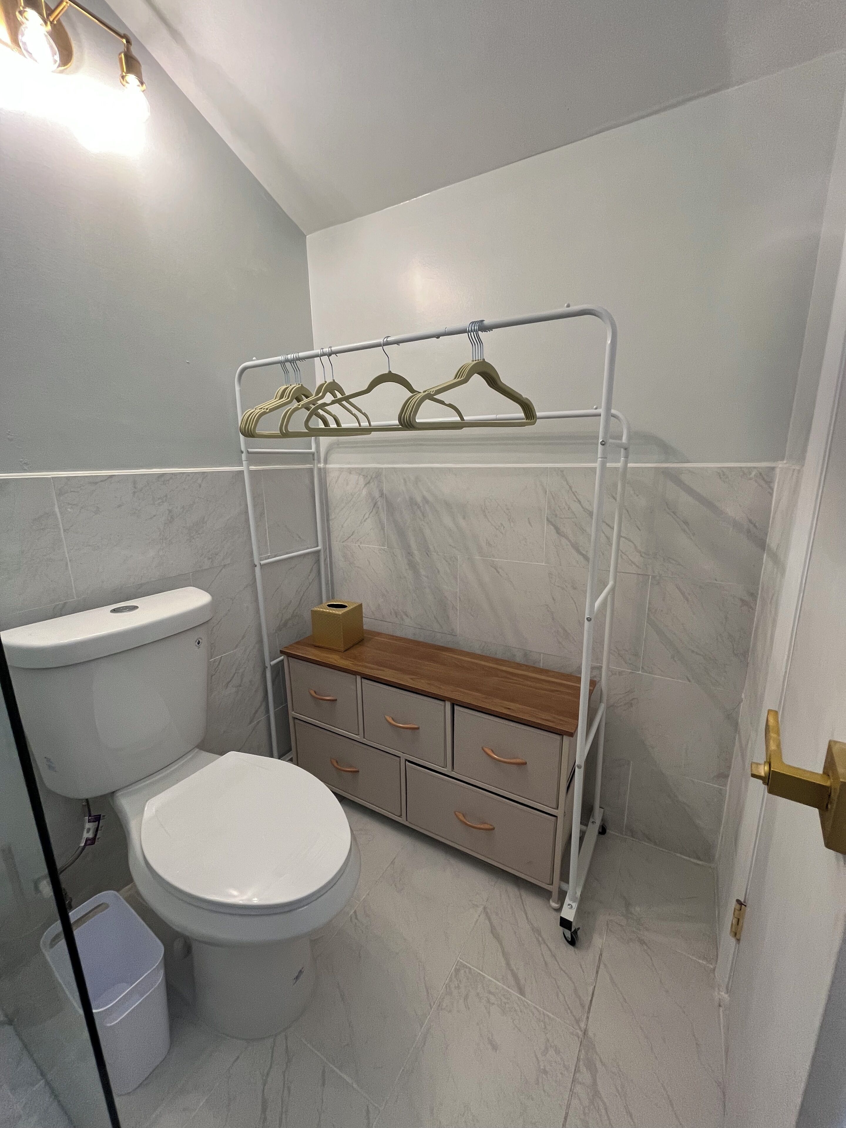 Un baño pequeño con inodoro, lavamanos y espacio de almacenamiento con cajones y repisas.