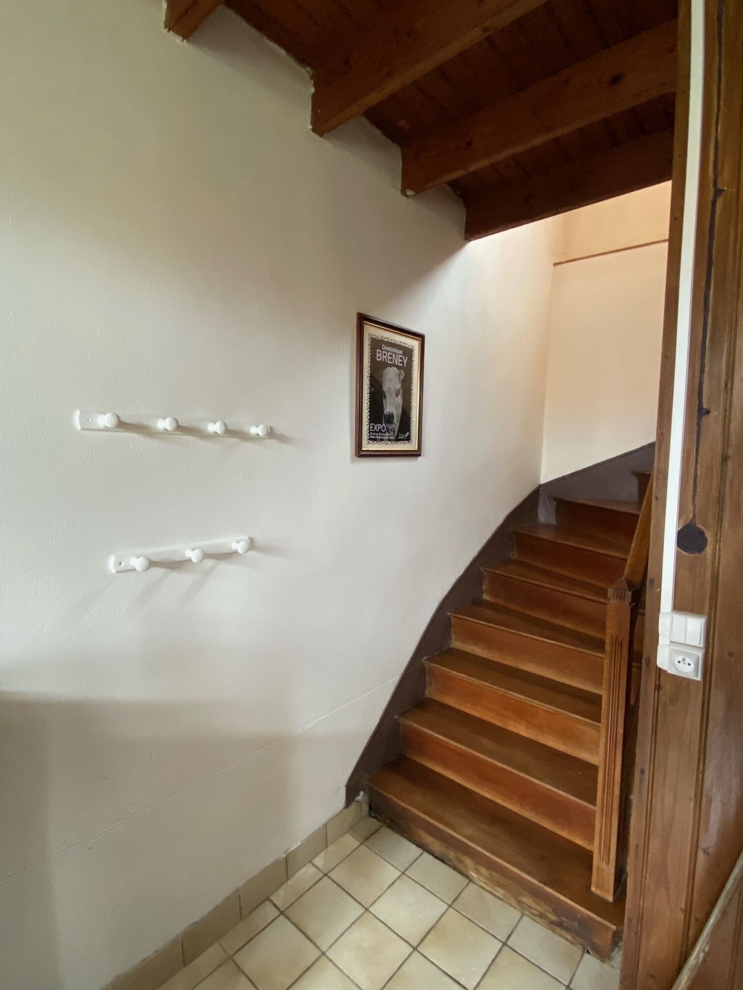 Eine Holztreppe mit einer weißen Wand und einem gerahmten Bild.