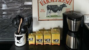 Een aanrecht met een koffiezetapparaat, een melkkruik, en een bordje met de tekst 'Boerenmelk Hier Vers Geserveerd'.