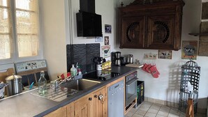 Een keuken met houten kastjes, een vaatwasser, een fornuis en een koffiezetapparaat.