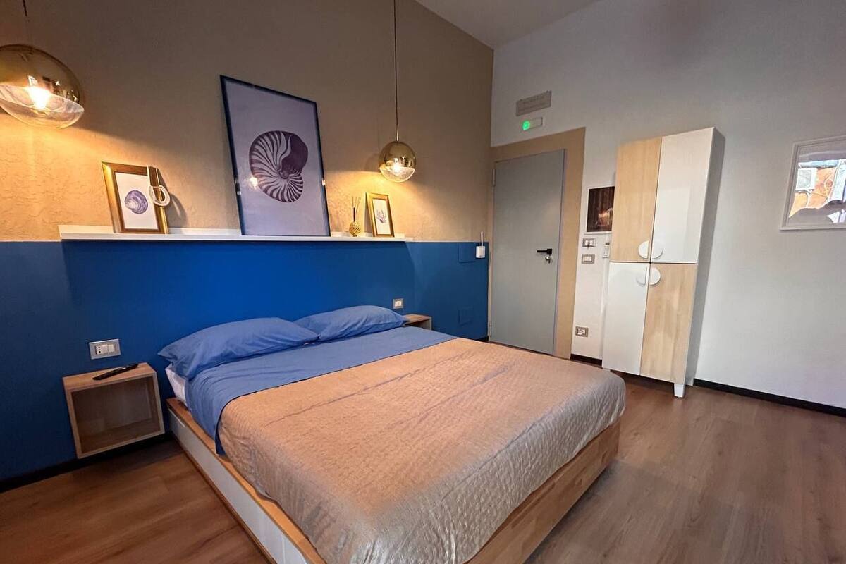 A bedroom with a bed, bedside tables, a wardrobe, and wall-mounted artwork.