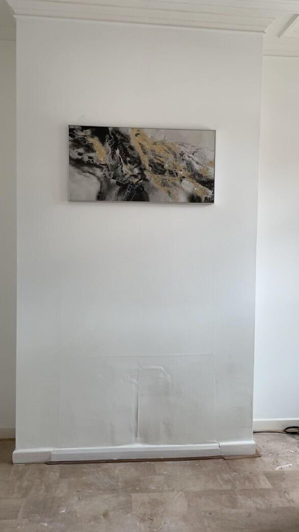 Une pièce dans laquelle on trouve un grand tableau abstrait au mur et un meuble blanc dont l’installation n’est pas tout à fait terminée.