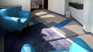 Un salon moderne avec un canapé bleu, un téléviseur à écran plat fixé au mur et un sol à motifs.