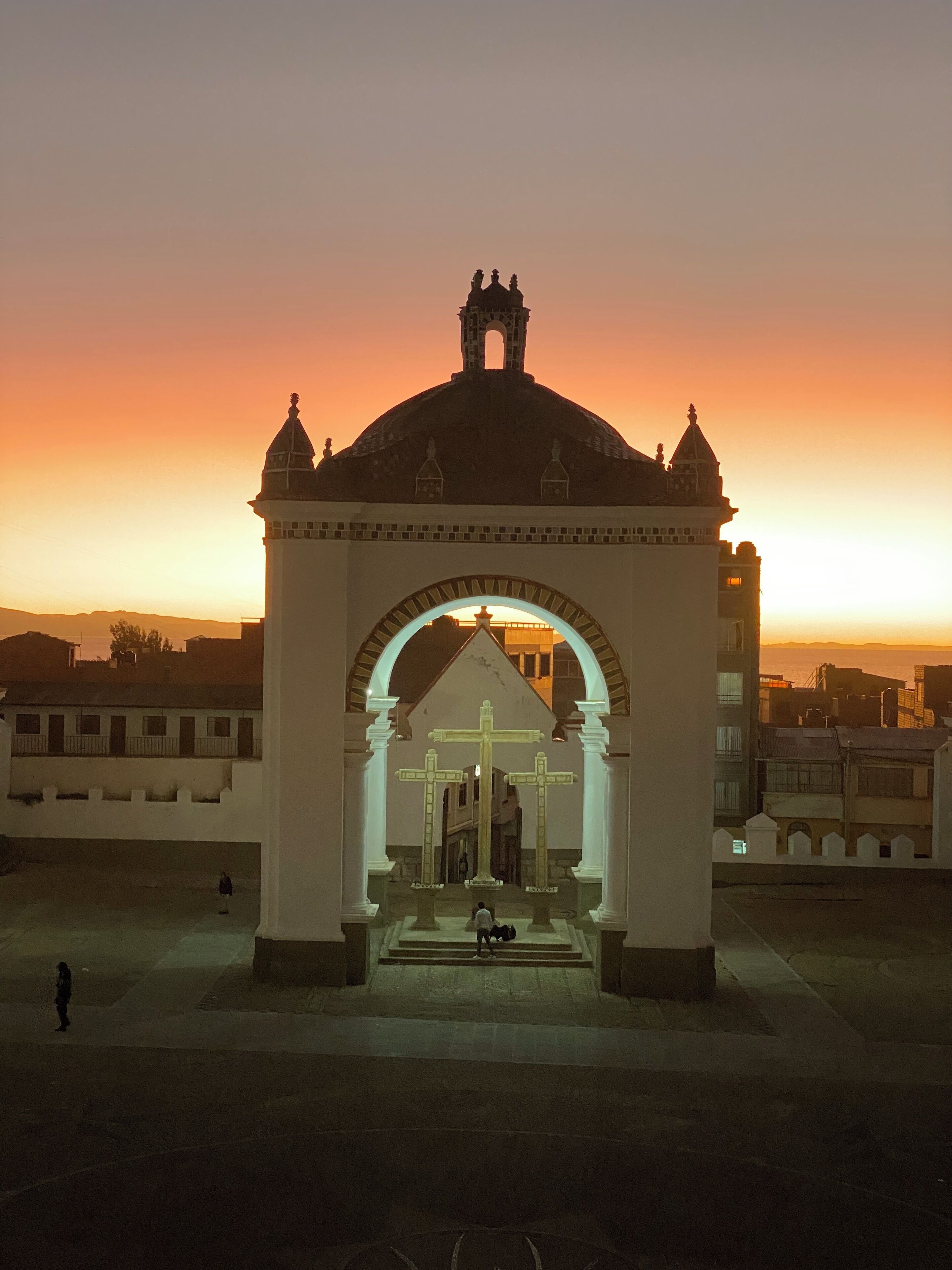 A historical building with a dome and a cross at its center, surrounded by a courtyard.