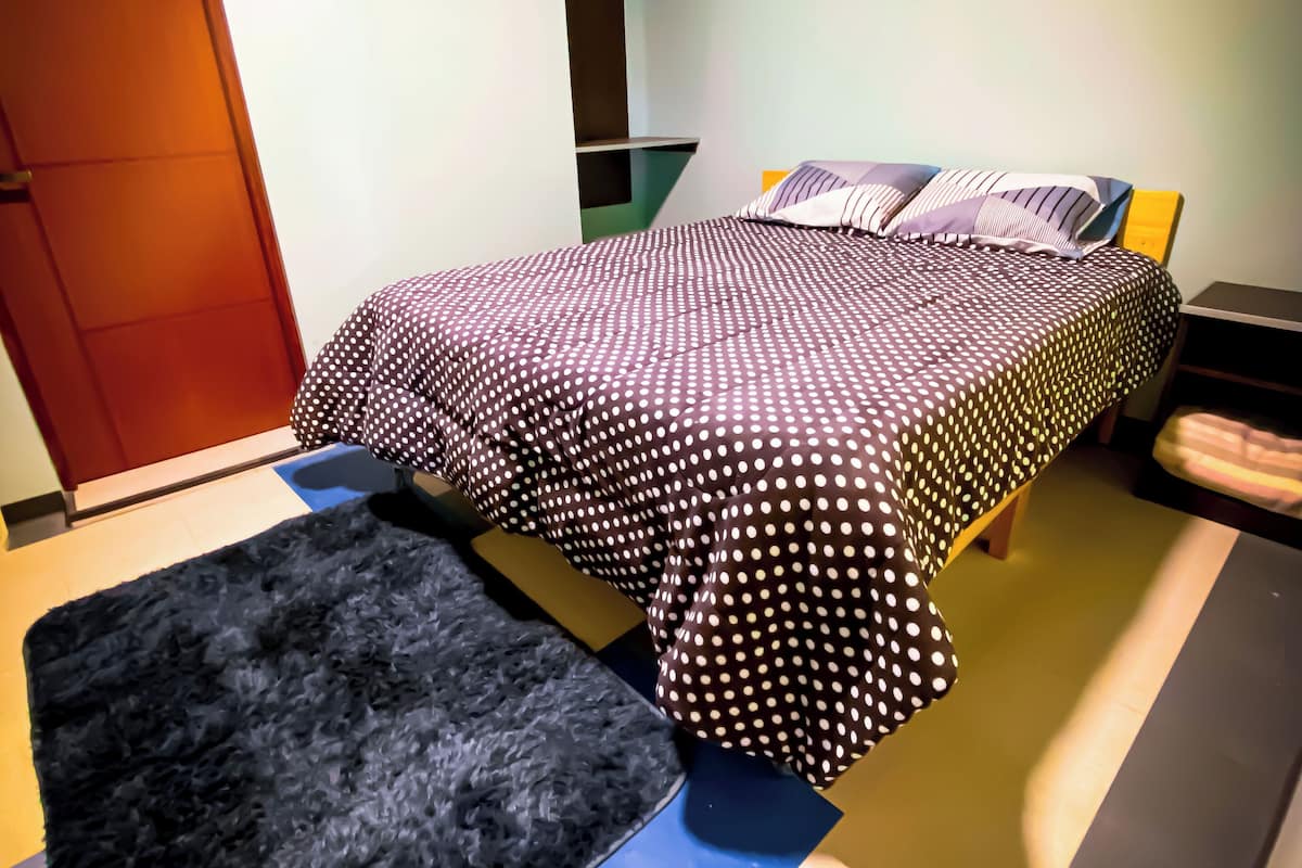 A bedroom with a bed, a black rug, and a wooden bench.