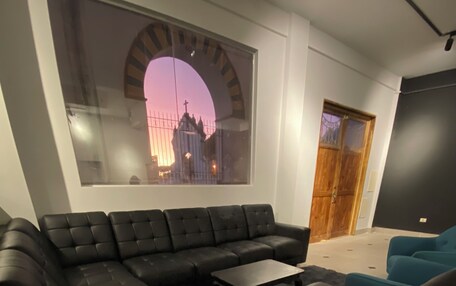 A modern living room with a sectional sofa, a coffee table, and a large window with a cityscape view.