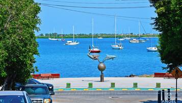A waterfront view with boats, a statue, and a pedestrian path.