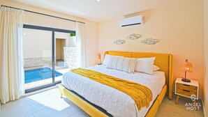 A bedroom with a bed, a nightstand, an air conditioner, and a view of a swimming pool through a sliding door. - Cozy Stay with onsite Pool Near Malecon (La Paz)