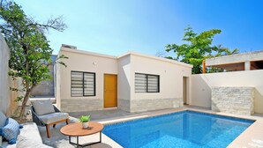 A modern pool area with a built-in pool, outdoor seating, and a small table. - Cozy Stay with onsite Pool Near Malecon (La Paz)