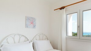 Un dormitorio con cama, cortinas blancas, una ventana y una obra de arte en la pared.