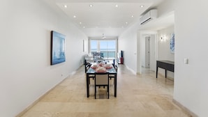 A spacious corridor with a dining area featuring a table set for four, a ceiling with recessed lighting, and a view to the outside. - Kite Beach Oceanfront condo  Hot tub and Pool 204 (Kite Beach)