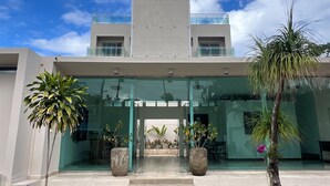 A modern building with a glass entrance, potted plants, and a clear sky. - Kite Beach Oceanfront condo  Hot tub and Pool 204 (Kite Beach)