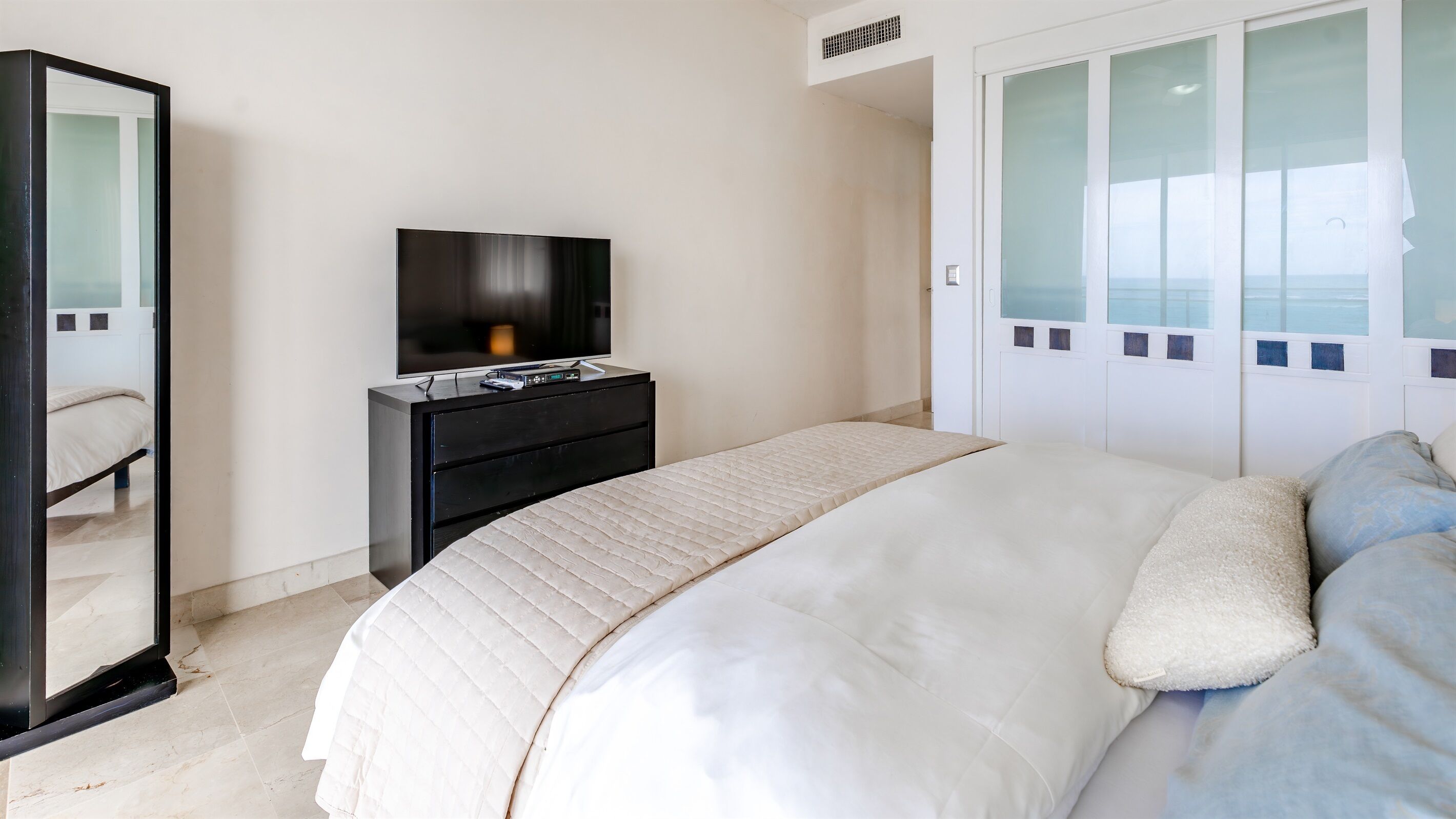 Un dormitorio con cama, cómoda, televisor y armario.