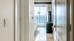 Corredor de hotel com vista para o mar através de uma porta de vidro.