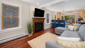 A spacious living room with a fireplace, a large TV, and a grey sofa.